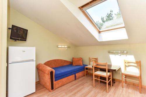 a room with a bed and a table and a refrigerator at Nakvynė pas Romą in Nida