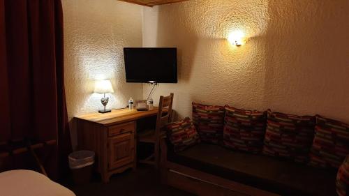 a room with a desk with a television on a wall at Auberge de Savoie in Moutiers
