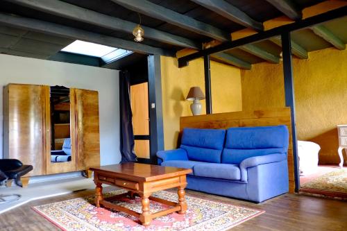 a living room with a blue couch and a table at Chambres d'hôtes des Forges in Cellefrouin