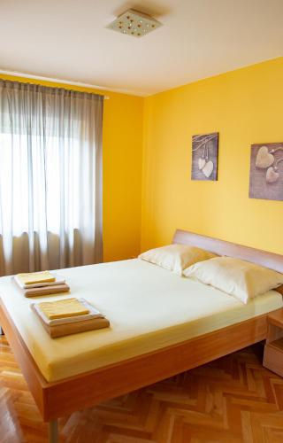 a bedroom with a large bed with yellow walls at Apartments Neda in Kampor