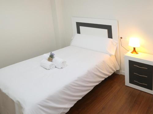 sypialnia z białym łóżkiem i 2 ręcznikami w obiekcie Apartamento puente romano P2 1G w Salamance