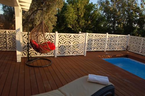 a wooden deck with a hammock next to a pool at Zimmerke in Bruchim Qela' Alon