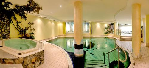 a swimming pool with a tub in a building at Hotel Kristall in Falzes