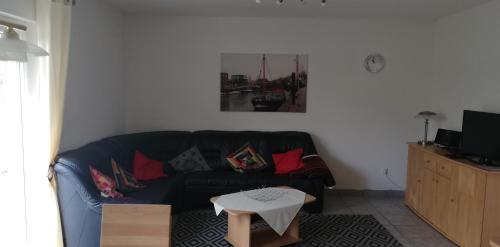 a living room with a black couch and a table at Ferienhaus Apfelblüte in Twielenfleth