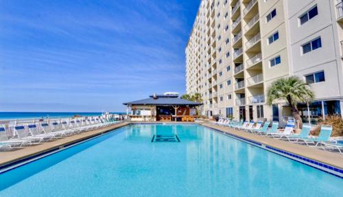 a swimming pool at a resort with chairs and the ocean at Regency Towers - beachfront condo in Panama City Beach