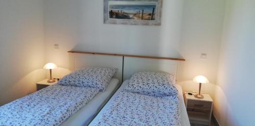 two beds in a small room with two lamps at Ferienhaus Apfelblüte in Twielenfleth