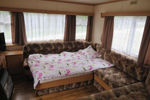 a couch with a bed in a room with windows at Leśny Zakątek Radocza in Radocza