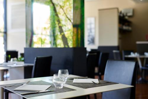 a table in a restaurant with a glass on it at Novotel Genova City in Genova