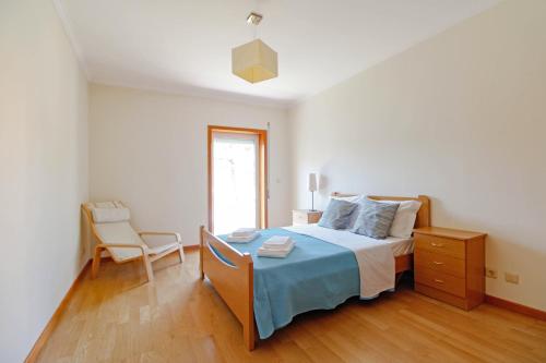 a bedroom with a bed and a chair in it at Senhora das Areias - Spacious Apt near the Cabedelo Beach in Viana do Castelo