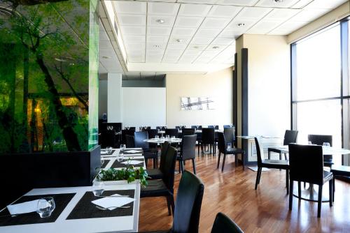 a dining room with tables and chairs and large windows at Novotel Genova City in Genova