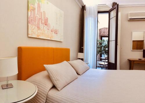 Un dormitorio con una cama blanca y una mesa. en Sangiuliano114 B&B, en Catania
