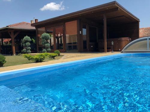 a large blue swimming pool in front of a house at Virág Vendégház in Hercegkút