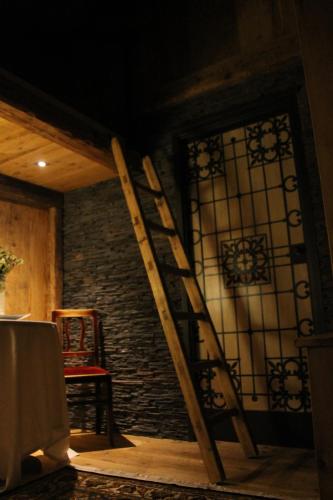 a wooden ladder in a room with a stained glass window at Locanda dei gentili in Ossana