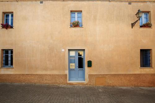 a building with a blue door and three windows at Ventanas in Villamassargia