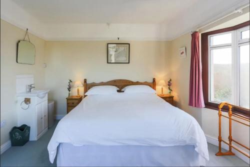 a bedroom with a white bed and a window at Chy-an-Lowena in Crantock