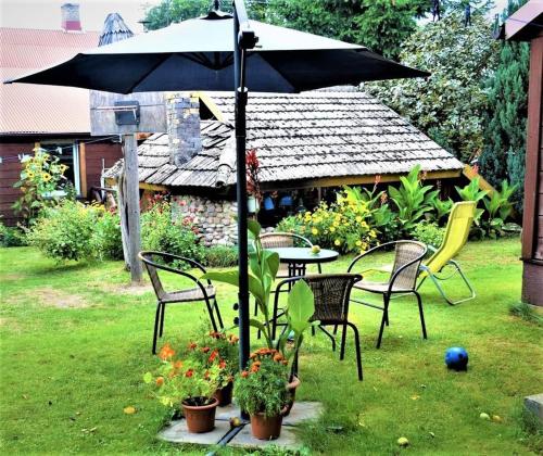 a table and chairs with an umbrella in a yard at Bogdanówka in Supraśl