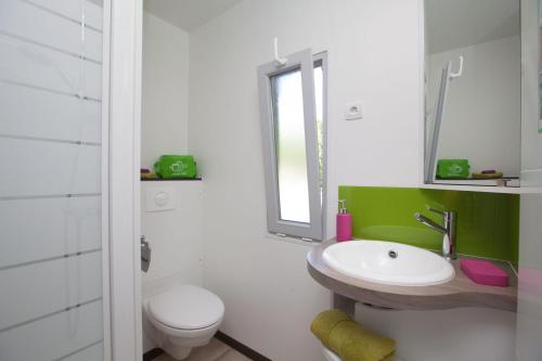 a white bathroom with a sink and a toilet at Mobil home Domaine de Soulac in Soulac-sur-Mer
