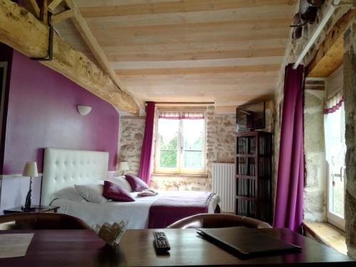 a bedroom with a bed with purple walls and a window at La Trainelière in Les Épesses