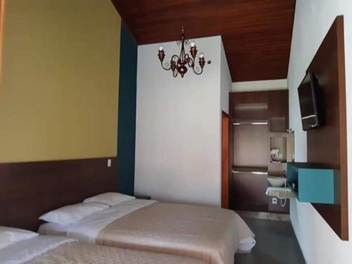 a bedroom with two beds and a chandelier at RECANTO MARIANE in Santo Antônio do Amparo