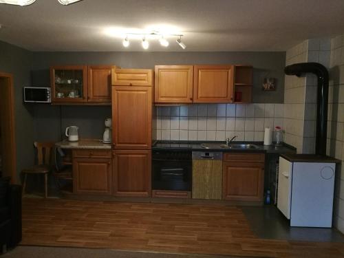La cuisine est équipée de placards en bois et d'un four avec plaques de cuisson. dans l'établissement Ferienwohnung zum Bergmann, à Annaberg-Buchholz