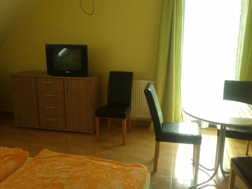 a living room with a tv and two chairs and a table at Határmenti Vendégház in Zsira