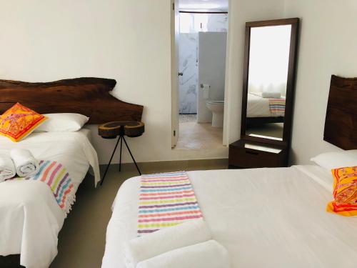 a bedroom with two white beds and a mirror at Casa Bizu in Bacalar