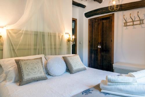 a bedroom with a bed with white sheets and pillows at Casa Tita María in Bubión