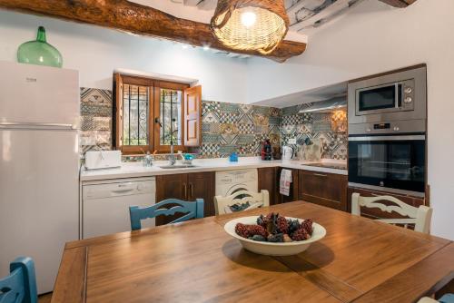 a kitchen with a wooden table with a bowl of fruit on it at Casa Tita María in Bubión