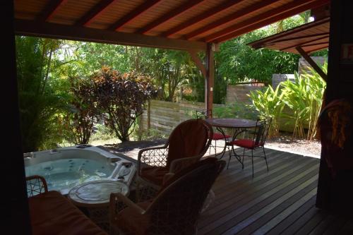 a hot tub on a deck with a table and chairs at Middle Country 97-1 "la recette du bonheur" in Deshaies