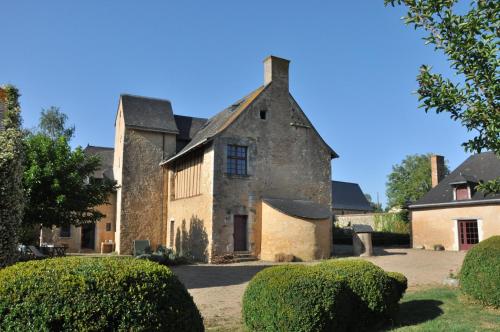 un ancien bâtiment en pierre avec des buissons devant lui dans l'établissement Manoir de la Croix Verte, à Le Bailleul