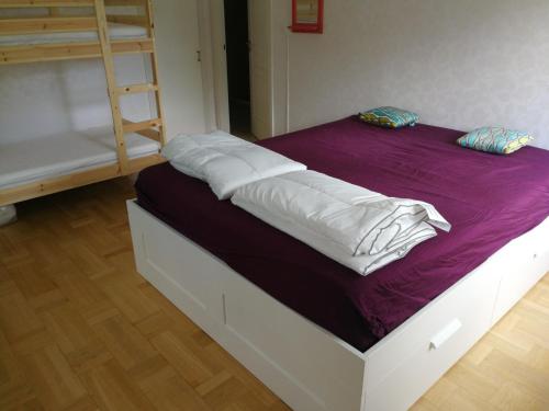 a bed with white sheets and a purple blanket at Skulebergets Frestelse in Docksta