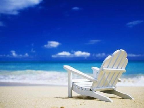 a white beach chair sitting on the beach at The Beach on Longboat Key in Longboat Key