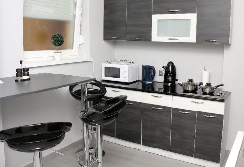 a kitchen with black stools and a counter with a microwave at CentRoom Apartman in Sátoraljaújhely