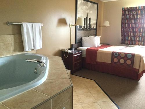 um quarto de hotel com uma cama e uma banheira em Super 8 by Wyndham Imlay City em Imlay City