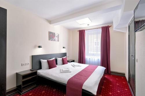 モスクワにあるРОС ОТЕЛЬ Измайловоのベッドと赤いカーペットが備わるホテルルーム