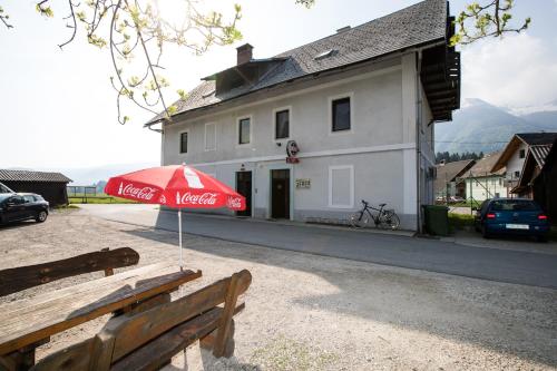 a red umbrella sitting on a bench in front of a building at APARTMA KAMNJE in Bohinj