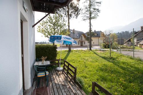 um alpendre com uma mesa e um guarda-chuva em APARTMA KAMNJE em Bohinj