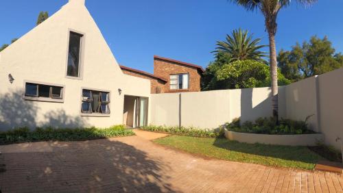 una casa blanca con una valla y una palmera en Ginger Barn, en Pretoria