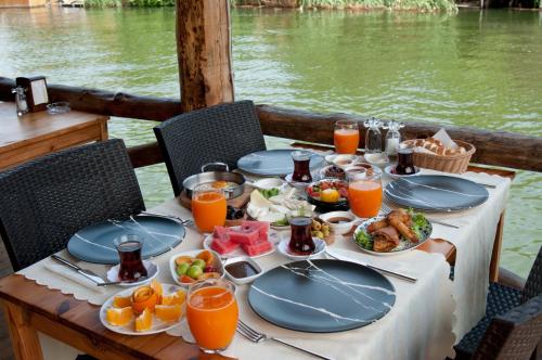 a table with plates of food and orange juice at Agva Gizemli Nehir Hotel in Ağva