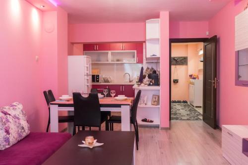 a living room with a table and a kitchen with pink walls at Apartment Nicole in Varna City