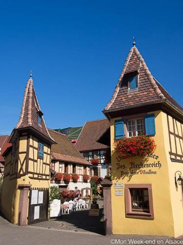 a yellow building with a building with a roof at Aux deux hirondelles in Houssen