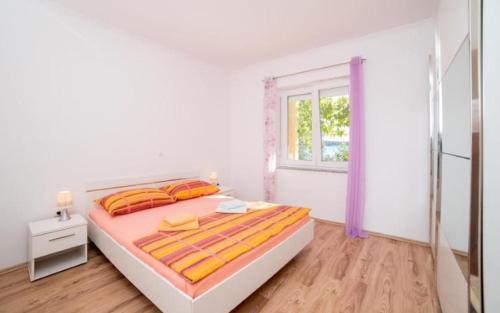 a white bedroom with a bed and a window at Apartmani Slavica in Rab
