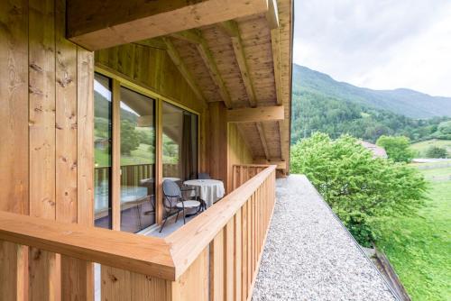 a wooden house with a balcony with a table and chairs at Hotel Taufers in Molini di Tures