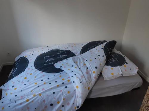 Una cama con sábanas de lunares y almohadas. en Elbeuf Etage 1 sweet home Netflix wifi, en Elbeuf