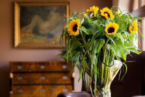 a vase filled with sunflowers sitting on a table at Hotel Selsky Dvur - Bohemian Village Courtyard in Prague