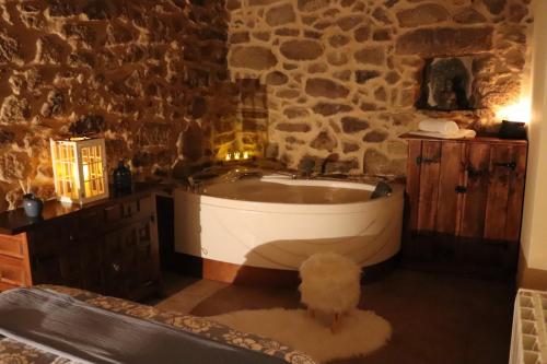 a bathroom with a tub and a stone wall at Apartamentos Casa do Bouza Vello in Sober