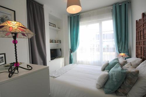 um quarto com uma cama com um candeeiro e uma janela em Le Petit Marais em Isigny-sur-Mer