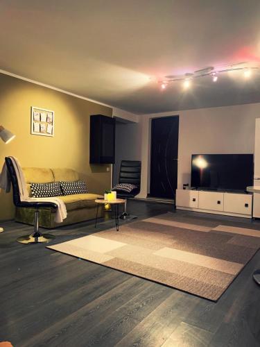 uma sala de estar com um sofá e uma televisão de ecrã plano em Lux Apartament em Zalău