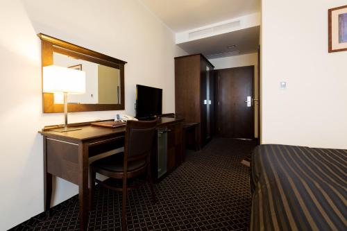 a hotel room with a desk and a bed at Hotel Selsky Dvur - Bohemian Village Courtyard in Prague