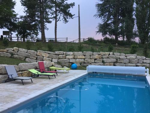 una piscina con 2 sillas de césped y una piscina en Le Moulin de Saint-Julien, en Saint-Didier-sur-Chalaronne